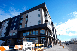 A person sweeps outside during the grand opening of the Rose on Colfax, a new affordable housing community with a co-located childcare center in the East Colfax neighborhood, Jan. 24, 2024, in Denver. (AP Photo/David Zalubowski, File)