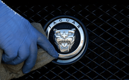 A worker polishes a Jaguar logo on a car at a Jaguar dealer in London, Wednesday Sept. 28, 2016. (AP Photo/Frank Austin, File)