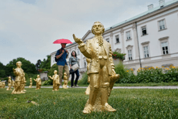 People pass 400 gold colored plastic Mozart sculptures by German artist Ottmar Hoerl from Nuremberg before the 270th birthday of composer Wolfgang Amadeus Mozart in Salzburg, Austria, Wednesday, July 15, 2026. (AP Photo/Matthias Schrader)