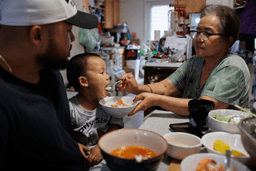 Lien Chang feeds her 2-year-old grandson Cairo Miu a bowl of rice next to his dad Jack Chang in her home on Monday, July 13, 2026, in San Francisco. (AP Photo/Juliana Yamada)