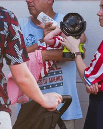 A woman holds a fan in front of a bottle-fed baby at the Great American State Fair, during an extreme heat wave, Friday, July 3, 2026, on the National Mall in Washington. (AP Photo/Julia Demaree Nikhinson)