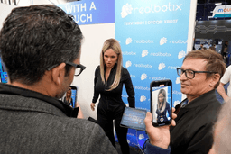 A Realbotix humanoid robot, center, speaks with attendees at a Realbotix booth during the CES tech show Jan. 8, 2025, in Las Vegas. (AP Photo/Abbie Parr, File)