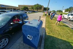 A person drops envelopes into a mailbox as postal workers participate in a national day of action outside a U.S. Post Office building, Tuesday, July 28, 2026, in Fort Worth, Texas. (AP Photo/Julio Cortez)