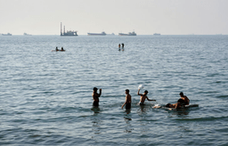 Residents swim and play in the waters of the Strait of Hormuz while cargo ships and commercial vessels lie anchored in the distance off Bandar Abbas, Iran, Wednesday, June 10, 2026.(Razieh Poudat/ISNA via AP)