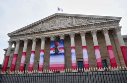 The French National Assembly is draped with the artwork "Marianne rêve" ("Marianne Dreams") by French street artist Seth, depicting Marianne the symbol of the French Republic, before lawmakers vote later on final approval of a bill allowing adults with incurable illnesses to receive lethal medication, in Paris, Wednesday, July 15, 2026. (AP Photo/Michel Euler)