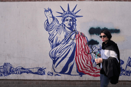 A woman walks past an anti-American mural on the wall of the former U.S. Embassy, now a museum, in Tehran, Iran, Friday, June 12, 2026. (AP Photo/Vahid Salemi)